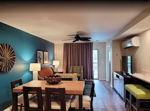 Quarto de hotel com área de jantar, ventoinha no teto, ar condicionado e televisão.