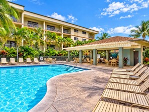 A hotel pool area with a clear blue pool, lounge chairs, and a covered seating area. - Big Island Resort - Beautiful one bedroom in Kailua-Kona (Kailua-Kona)