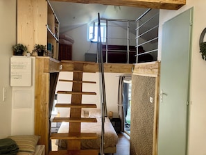 Ein Schlafzimmer im Loft-Stil mit einer Holztreppe, einem Etagenbett und einer kleinen Schreibtischzeile.