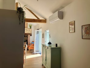 Ein Flur mit Holzboden, einem grünen Schrank und einer Tür zu einem Raum mit Kamin aus Ziegeln.
