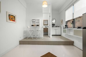A modern kitchen with white cabinetry, a dining area with chairs, and a small table. - San Rafael Apt 6 | Cozy 1 BR Retreat @ San Juan (San Juan de Puerto Rico)