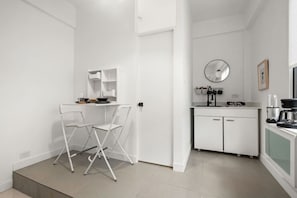 A compact kitchen with a dining area, white cabinetry, a sink, and a coffee machine. - San Rafael Apt 6 | Cozy 1 BR Retreat @ San Juan (San Juan de Puerto Rico)