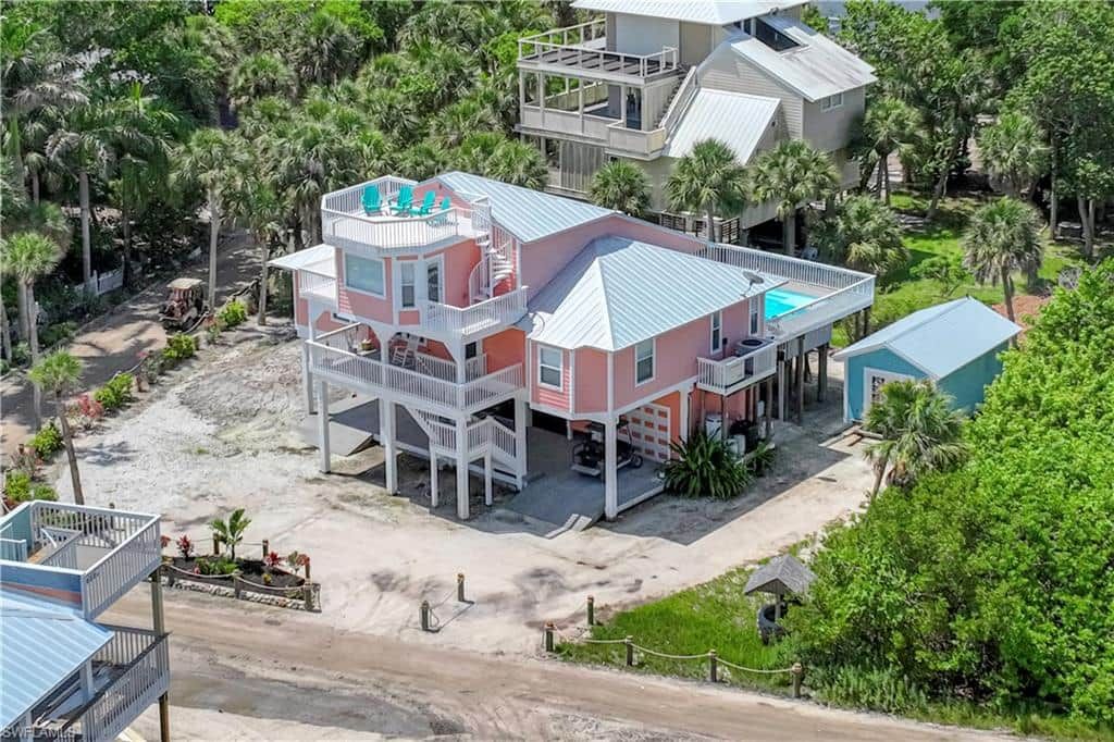 A multi-story beachfront property with a pool, multiple decks, and a beach access area.