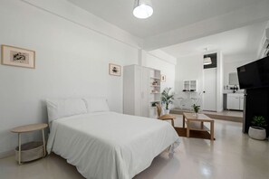 A modern, minimalist hotel room with a large bed, a small desk, a wardrobe, and a separate bathroom area. - San Rafael Apt 7 | Chic Comfort Place @San Juan (San Juan de Puerto Rico)