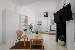 A modern living space with a dining area, a TV mounted on the wall, and a kitchen in the background. - San Rafael Apt 7 | Chic Comfort Place @San Juan (San Juan de Puerto Rico)