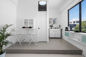 A compact kitchenette with a sink, cabinets, and a window overlooking a cityscape. - San Rafael Apt 7 | Chic Comfort Place @San Juan (San Juan de Puerto Rico)
