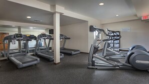Ein Fitnessstudio mit Laufbändern, Crosstrainern und einer Gewichtbank.
