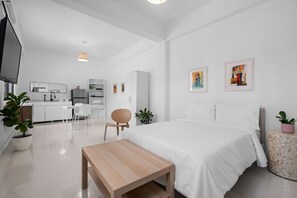 A modern, white-themed hotel room with a bed, bedside table, and a small desk area. - San Rafael Apt 8 | Elegant 1 BR Stay @ San Juan (San Juan de Puerto Rico)