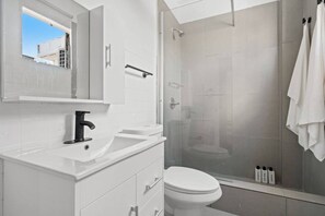 A modern bathroom with a white sink, mirror, and toilet. - San Rafael Apt 8 | Elegant 1 BR Stay @ San Juan (San Juan de Puerto Rico)