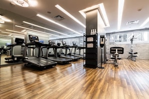 A gym with treadmills, weight machines, and a wooden floor. - Skyline 2BR Suite in Yorkville • 2 Baths & Kitchen (Toronto)
