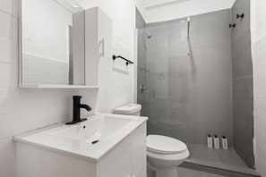 A modern bathroom with a white sink, toilet, and a glass-enclosed shower area. - Casa San Rafael Apt 9 | Contemporary 2BR Hideaway (San Juan de Puerto Rico)