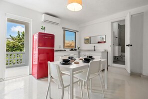 A modern kitchen with a red refrigerator, white dining table, and chairs. - Casa San Rafael Apt 9 | Contemporary 2BR Hideaway (San Juan de Puerto Rico)