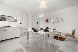 A modern kitchen with white cabinetry, a dining table set for four, and a pendant light above. - Casa San Rafael Apt 9 | Contemporary 2BR Hideaway (San Juan de Puerto Rico)