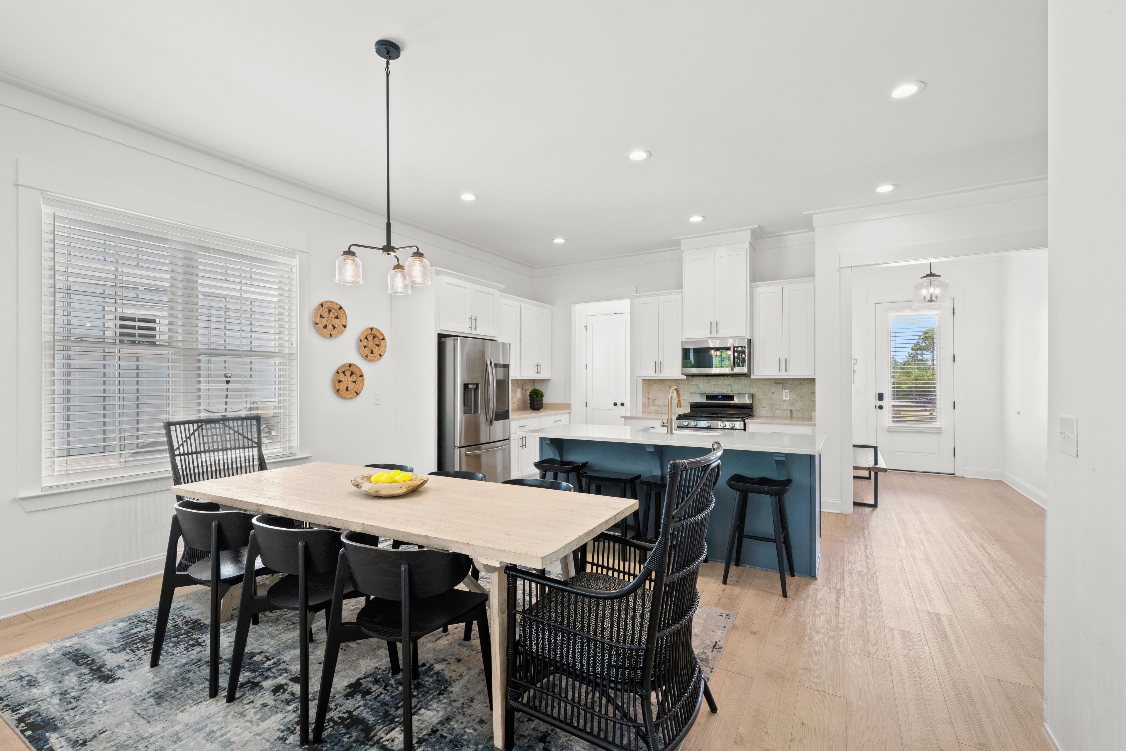 A modern kitchen with white cabinets, a central island, and a dining area with a table and chairs.
