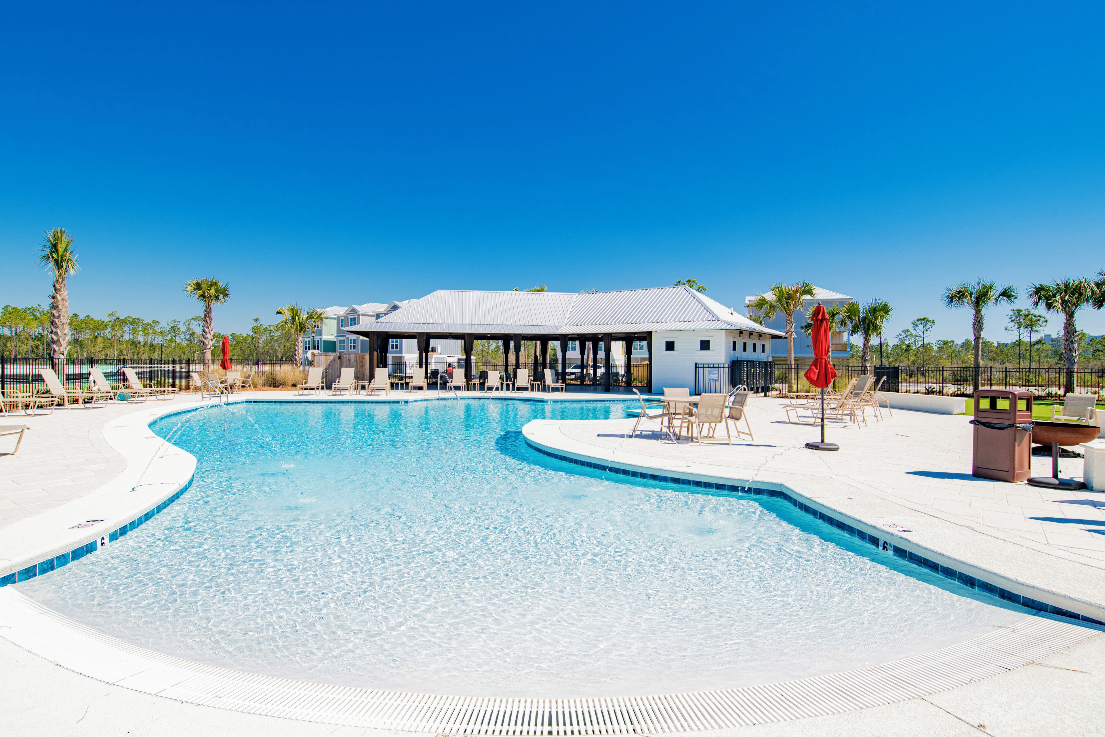 A swimming pool with lounge chairs and a covered pavilion.