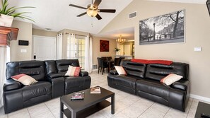 A living room with two black leather sofas, a coffee table, and a ceiling fan. - ATX Basecamp - Near The Domain & Q2 Stadium (Austin)