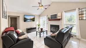 A modern living room with a fireplace, leather sofas, a coffee table, and a television. - ATX Basecamp - Near The Domain & Q2 Stadium (Austin)