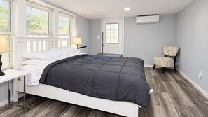A bedroom with a bed, bedside table, chair, and a door. - Cozy Georgetown 3BR Near Rehoboth Beach (Georgetown)
