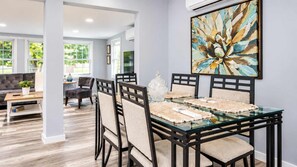 A dining area with a glass table, black chairs, and a large abstract painting on the wall. - Cozy Georgetown 3BR Near Rehoboth Beach (Georgetown)