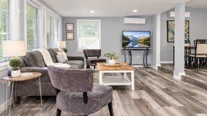 A modern living room with a grey sofa, a grey armchair, a wooden coffee table, and a flat-screen TV mounted on the wall. - Cozy Georgetown 3BR Near Rehoboth Beach (Georgetown)