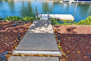 A concrete pathway leading to a dock over water, surrounded by a garden with fallen leaves. - Clearlake Oaks - Boat Slip, Views (Clearlake Oaks)