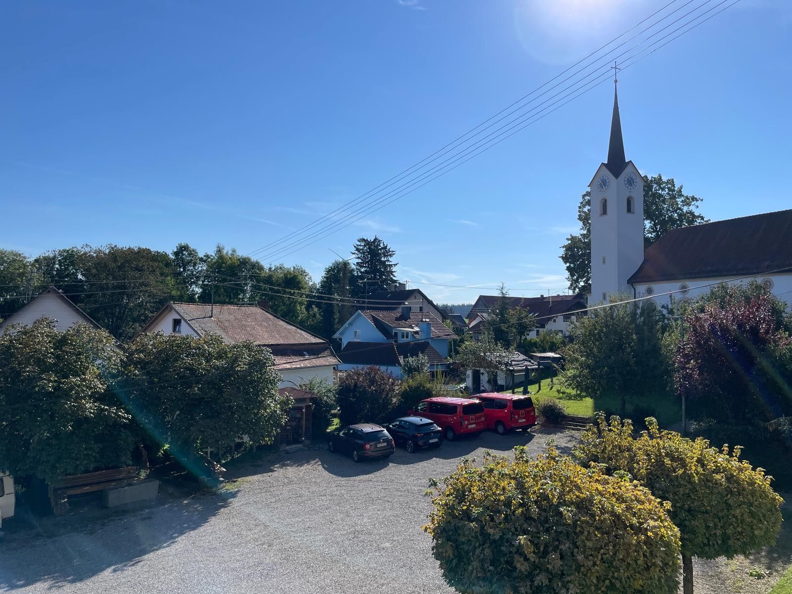 Ein Wohngebiet mit Kirche, Häusern und geparkten Fahrzeugen.