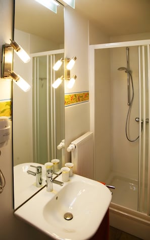 A bathroom with a white sink, mirror, and shower. - Studio Apartment 'Marleen' with Wi-Fi (Ottobeuren)