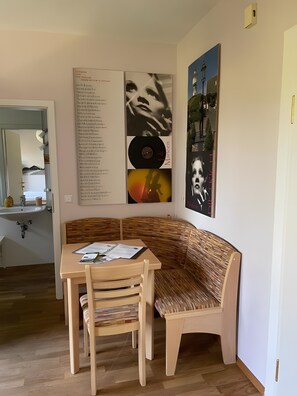 A room with a wooden bench, a table with papers, and wall art including a vinyl record. - Studio Apartment 'Marleen' with Wi-Fi (Ottobeuren)