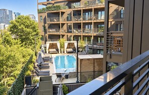 Ein modernes Apartmenthaus mit Pool auf dem Dach, Sitzgelegenheiten im Freien und Blick auf die Stadtlandschaft.