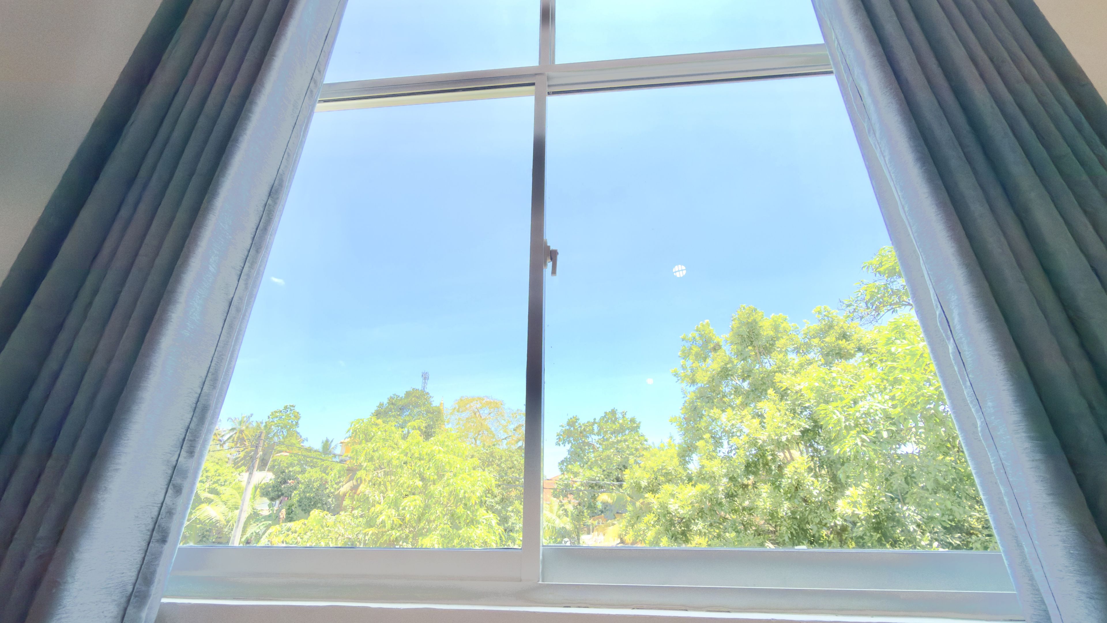 Una ventana con vistas a árboles y un cielo despejado.
