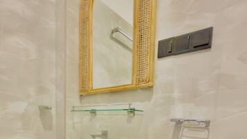 A bathroom with a white pedestal sink, a mirror with a woven frame, and a towel rack.