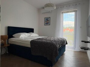 A bedroom with a bed, a chair, a window with curtains, and a wall-mounted air conditioning unit. - VISTA—a spacious 3-story apartment on the slopes of Karpacz; pets welcome (Województwo dolnośląskie)