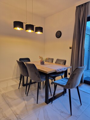 A dining area with a wooden table, grey upholstered chairs, and pendant lighting. - VISTA—a spacious 3-story apartment on the slopes of Karpacz; pets welcome (Województwo dolnośląskie)