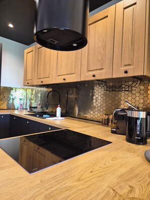 A modern kitchen with wooden cabinets, a black induction cooktop, a coffee maker, and a hexagonal backsplash. - VISTA—a spacious 3-story apartment on the slopes of Karpacz; pets welcome (Województwo dolnośląskie)