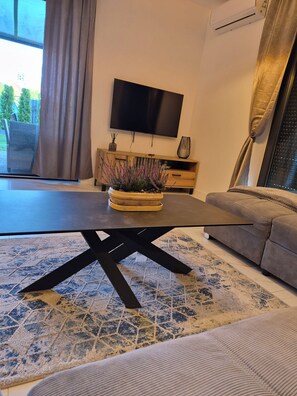 A modern living room with a large flat-screen TV, a sofa, a coffee table, and a potted plant. - VISTA—a spacious 3-story apartment on the slopes of Karpacz; pets welcome (Województwo dolnośląskie)