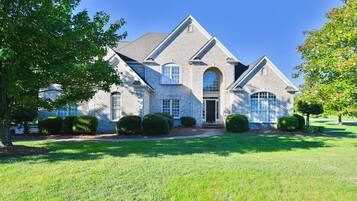 A large, two-story house with a symmetrical facade, a central entrance, and a well-maintained lawn.