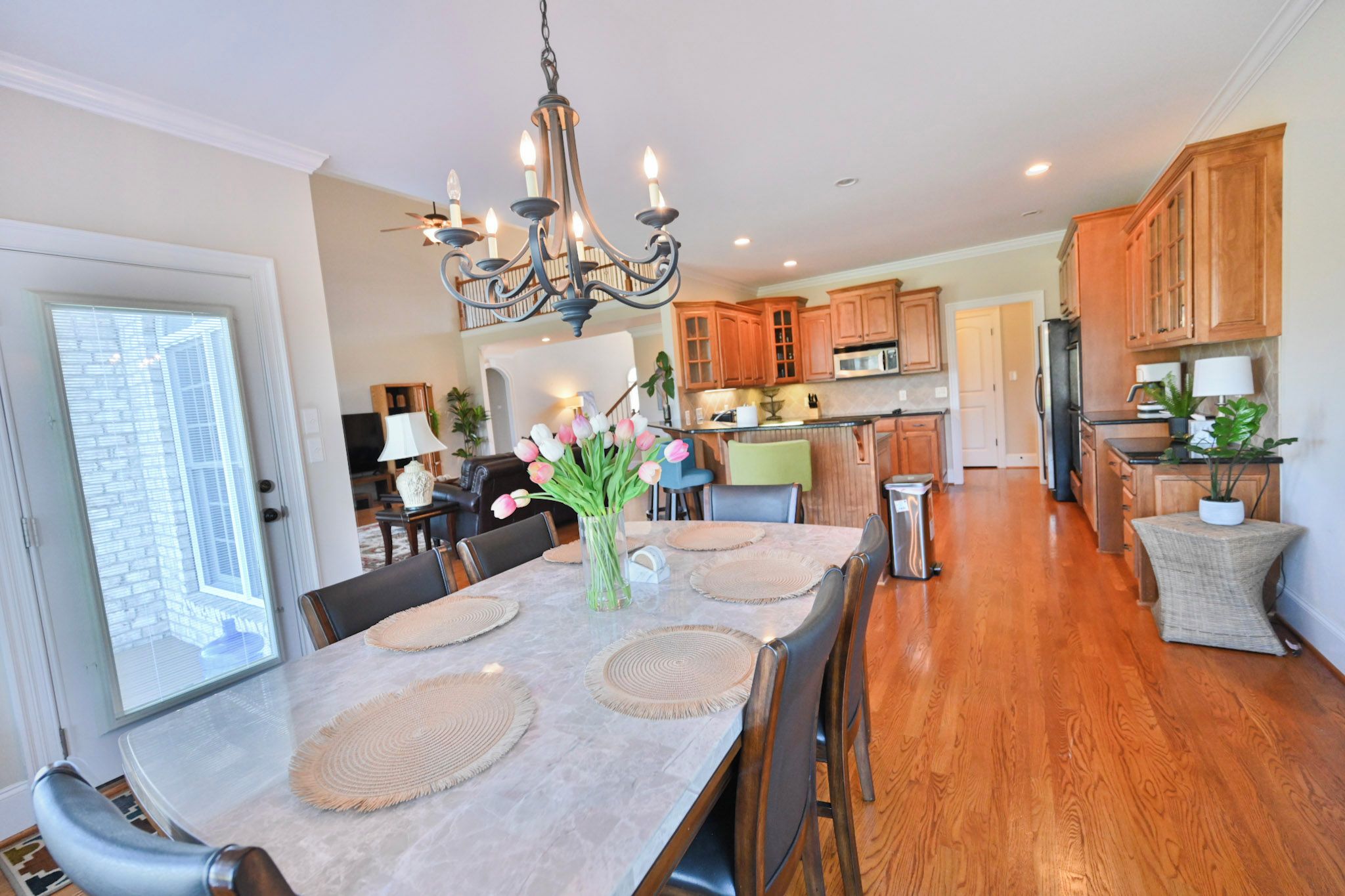 A spacious kitchen with wooden cabinets, a central island, and a chandelier.