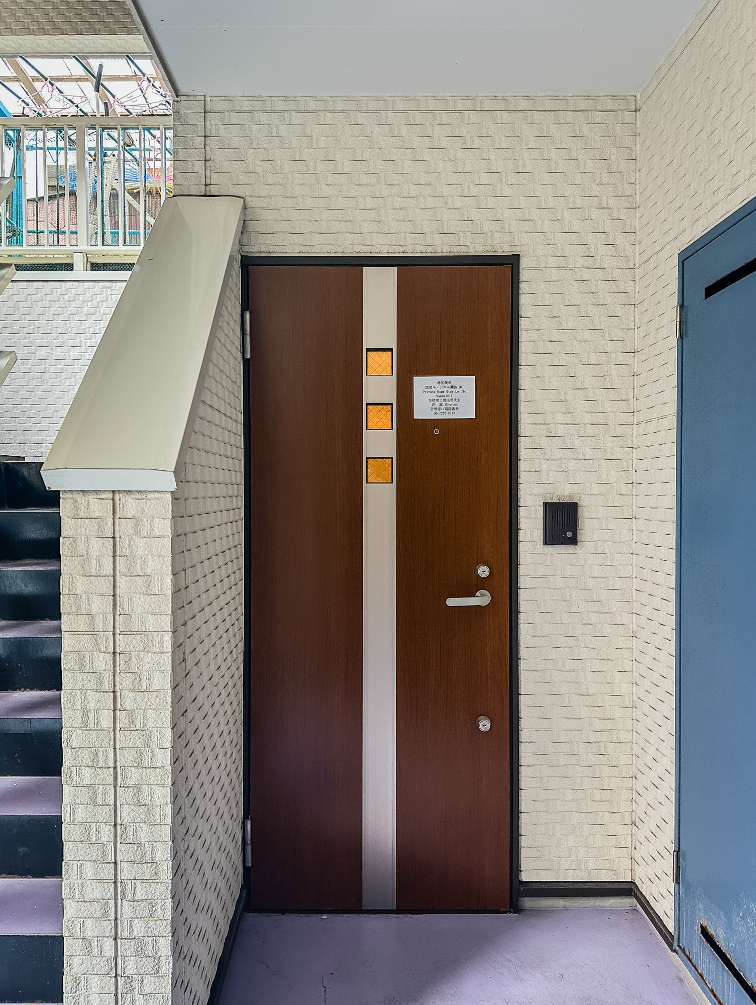 Una puerta de madera con una franja vertical, un letrero pequeño y un timbre.