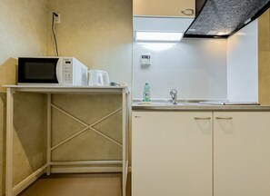 A kitchenette with a microwave, a small table, a sink, and cabinets. - HANASTAY MITSUHA & SEIRAN (Osaka)