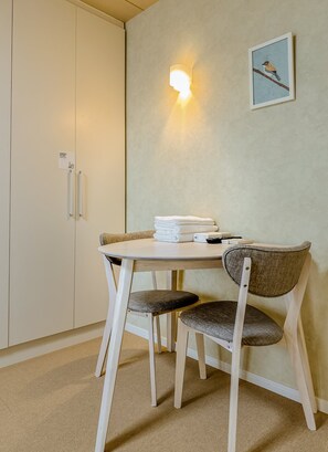 A small room with a round table, two chairs, a wall-mounted light, and a framed picture. - HANASTAY MITSUHA & SEIRAN (Osaka)