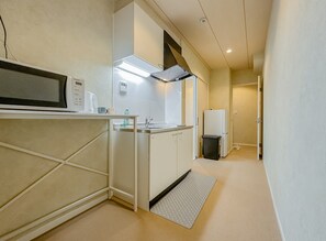 A compact kitchen with a microwave, coffee maker, and a small sink. - HANASTAY MITSUHA & SEIRAN (Osaka)