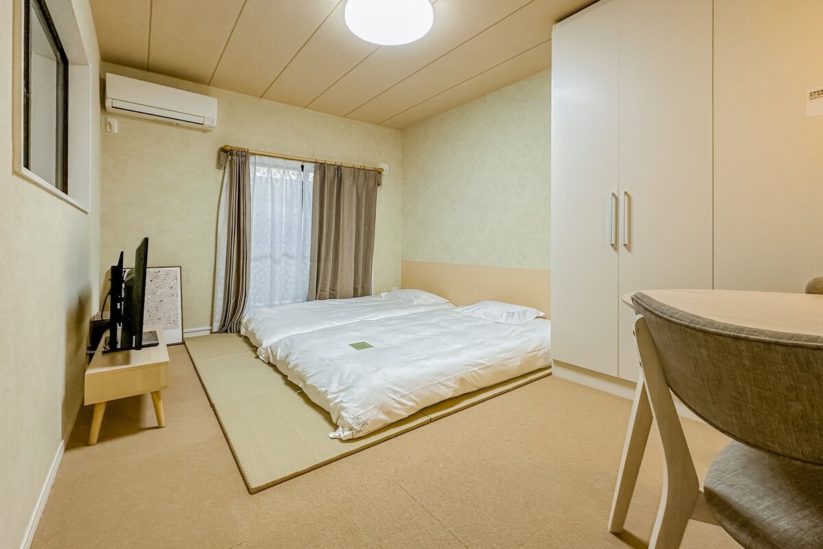 A hotel room with a bed, a desk, a chair, and a wardrobe.
