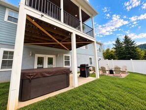 Ein zweistöckiges Haus mit einer überdachten Terrasse, einem Grill und Sitzgelegenheiten im Freien.