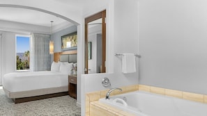 Quarto de hotel com duas camas, banheiro com banheira e vista para o exterior.