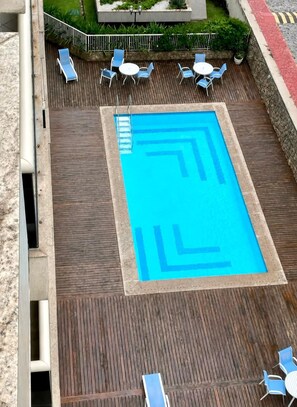 Una piscina al terrat amb dibuixos geomètrics blaus, envoltada de gandules blaves i una taula petita.