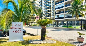 Ein Hotel Eingang mit einem Schild, das 'RAIA RIO 4666' zeigt, Palmen, einem Taxischild und einem modernen Gebäude im Hintergrund.