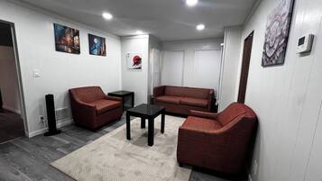 A living room with a sofa, armchairs, a coffee table, and artwork on the walls.