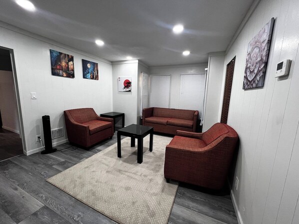 Una sala de estar con un sofá, sillones, una mesa de centro y obras de arte en las paredes.