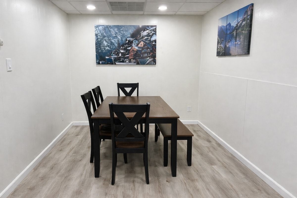 Une salle de conférence avec une table rectangulaire et quatre chaises, des murs blancs et deux tableaux.