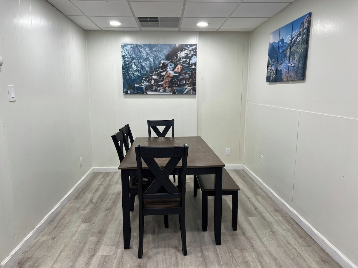 Een vergaderruimte met een rechthoekige tafel en vier stoelen, witte wanden en twee schilderijen.